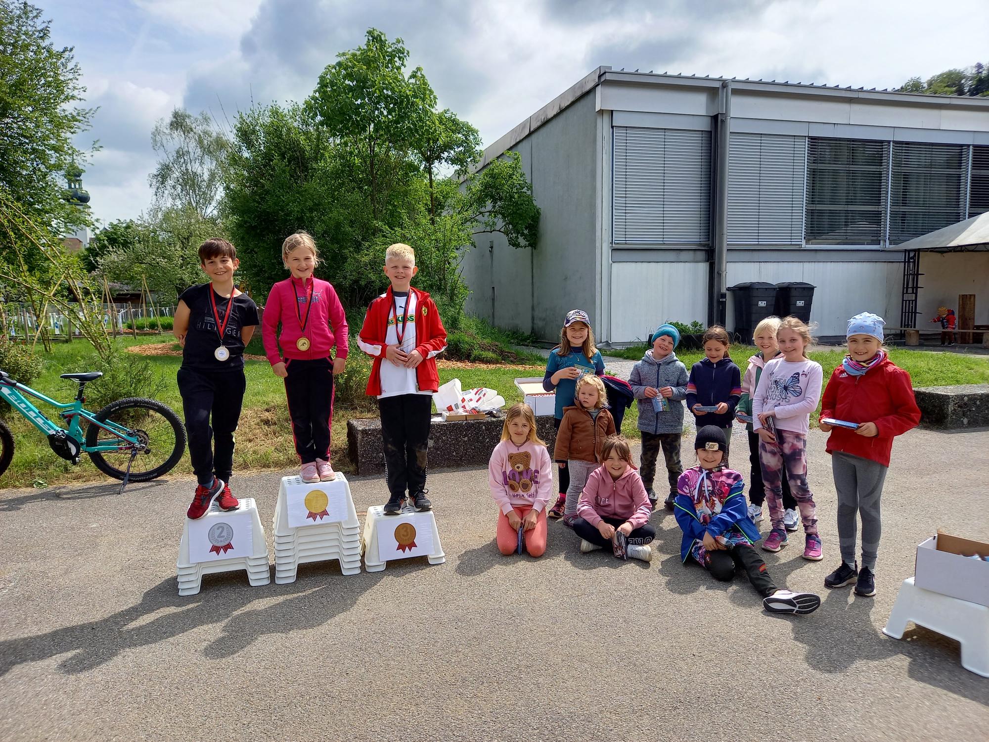 Trotz kalten Temperaturen führten wir den UBS KIDS CUP durch. Mit viel Engagement unterstützte uns wiederum Lisa Lisser. In drei Gruppen starteten die Kinder in den Disziplinen Sprint, Weitwurf und Weitsprung. Sogar unsere Jüngsten machten mit und gaben ihr Bestes.
In der Pause wärmten sich die zahlreichen Besucher und Besucherinnen bei einem Kaffee und nutzen die Gelegenheit, den neuen Kindergarten zu erkunden.
Währenddessen durften die Kinder frei spielen oder sich an den Gruppenspielen beteiligen. Es war eine gute, lustige Stimmung.
Pünktlich um halb zwölf zur Rangverkündigung schien die Sonne und es wurde deutlich wärmer.
Die Spannung blieb bis zum Schluss, wer wohl dieses Jahr aufs Podest steigen darf und eine Medaille bekommt. Alle haben einen super Einsatz geleistet!
Wir danken für die zahlreichen Besuche der Eltern, das Anfeuern und Mitfiebern. Es war auch dieses Jahr ein toller Sportmorgen. Herzlichen Dank Lisa für die wertvolle Unterstützung.
